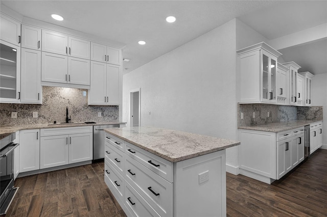 kitchen with white cabinetry, dishwasher, sink, light stone counters, and a kitchen island