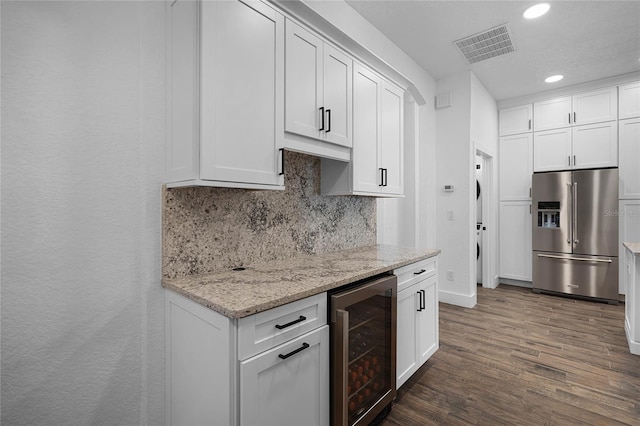 kitchen with wine cooler, high end refrigerator, dark hardwood / wood-style flooring, light stone counters, and white cabinets