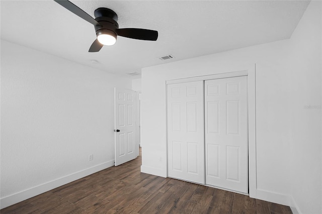 unfurnished bedroom with dark hardwood / wood-style flooring, a closet, and ceiling fan