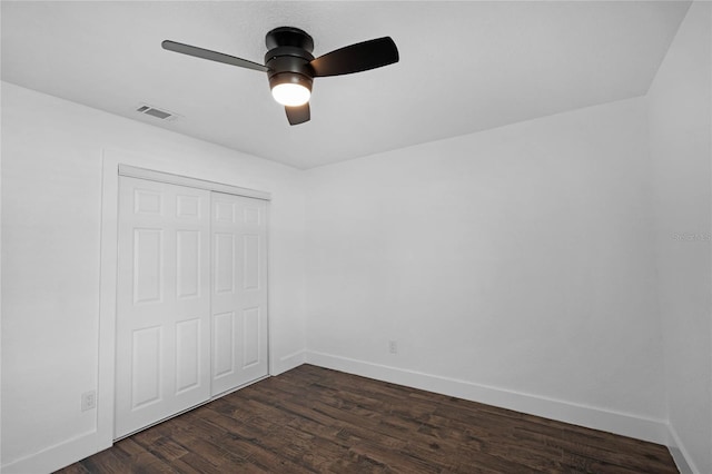 unfurnished bedroom with dark hardwood / wood-style flooring, a closet, and ceiling fan