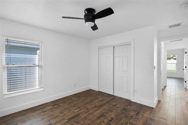 unfurnished bedroom with dark hardwood / wood-style flooring, a closet, and ceiling fan