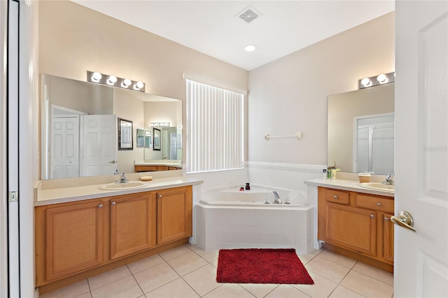 bathroom featuring tiled tub, vanity, and tile patterned floors