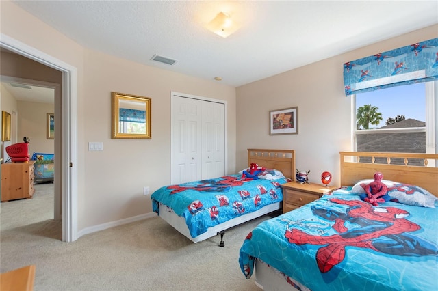 bedroom featuring light carpet, a textured ceiling, and a closet