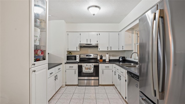 kitchen with white cabinetry, light tile patterned floors, a textured ceiling, stainless steel appliances, and sink