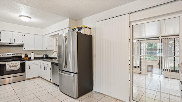 kitchen featuring light tile patterned floors, a textured ceiling, white cabinets, appliances with stainless steel finishes, and sink