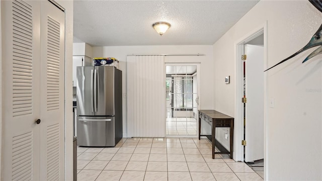 kitchen with light tile patterned flooring, stainless steel refrigerator, and a textured ceiling