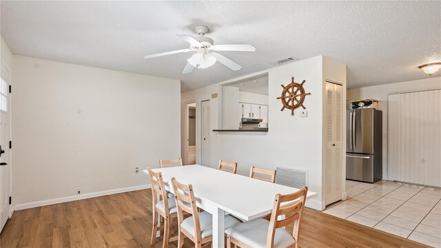 dining area with light hardwood / wood-style flooring, a textured ceiling, and ceiling fan