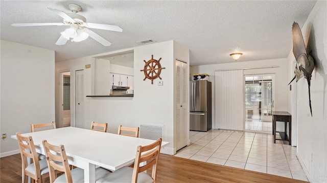 dining area with light hardwood / wood-style flooring, a textured ceiling, and ceiling fan