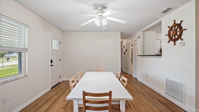 dining area with light hardwood / wood-style floors, a textured ceiling, and ceiling fan