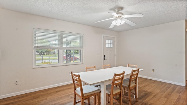 dining space with a healthy amount of sunlight, a textured ceiling, wood-type flooring, and ceiling fan