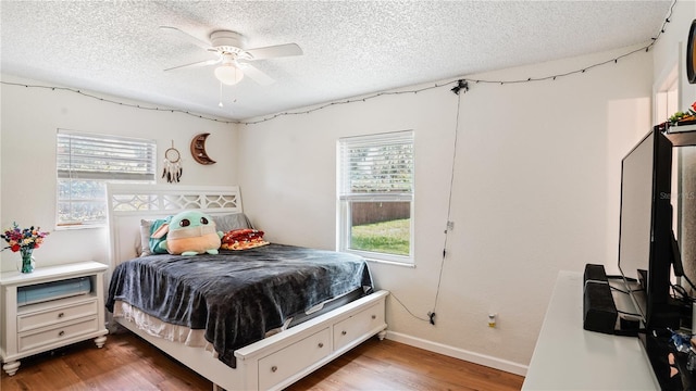 bedroom with a textured ceiling, ceiling fan, and hardwood / wood-style floors