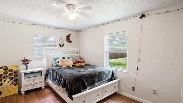 bedroom with a textured ceiling, wood-type flooring, and ceiling fan