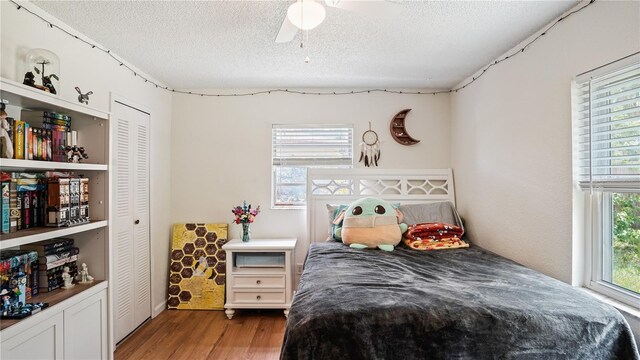 bedroom featuring wood-type flooring, a textured ceiling, a closet, and ceiling fan