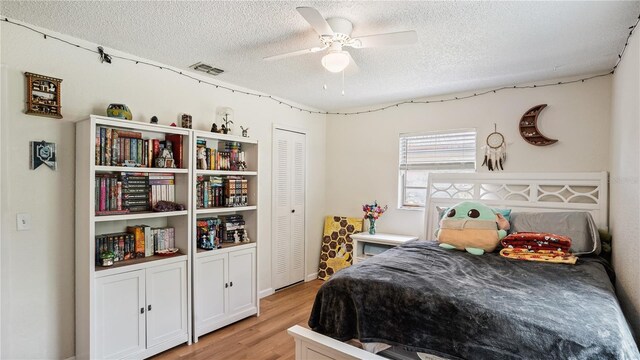 bedroom featuring light hardwood / wood-style floors, a textured ceiling, a closet, and ceiling fan