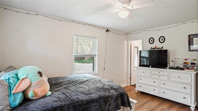 bedroom featuring a textured ceiling, light wood-type flooring, and ceiling fan