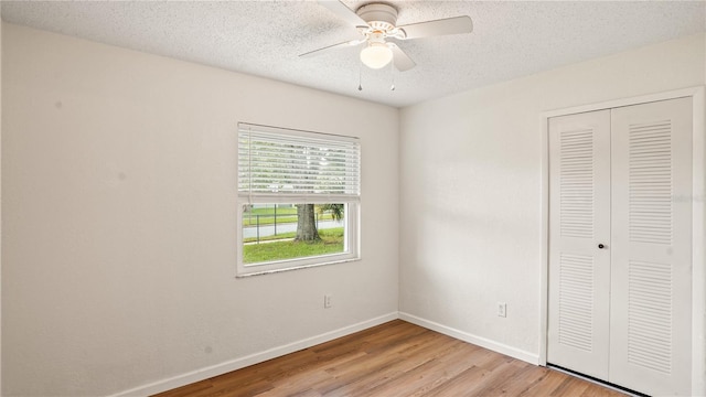 unfurnished bedroom featuring a textured ceiling, light hardwood / wood-style flooring, a closet, and ceiling fan