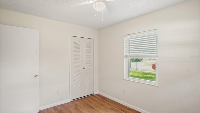 unfurnished bedroom featuring a closet, a textured ceiling, ceiling fan, and light wood-type flooring