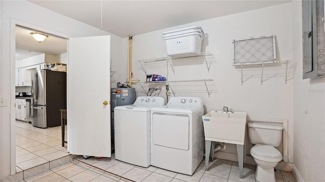 clothes washing area with electric water heater, separate washer and dryer, and light tile patterned floors