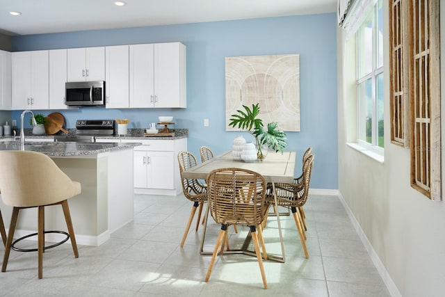 kitchen featuring dark stone countertops, light tile patterned flooring, stainless steel appliances, and white cabinetry