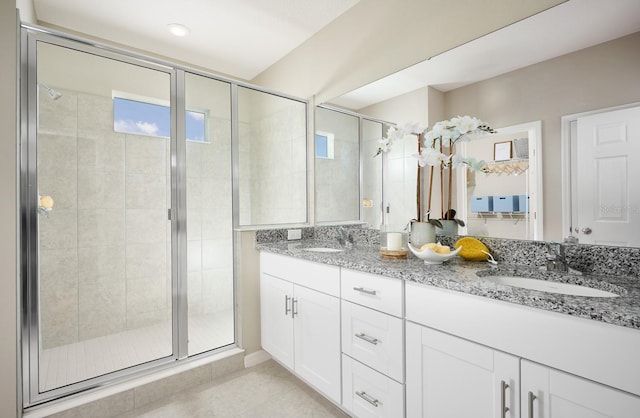 bathroom featuring a shower stall, double vanity, tile patterned floors, and a sink