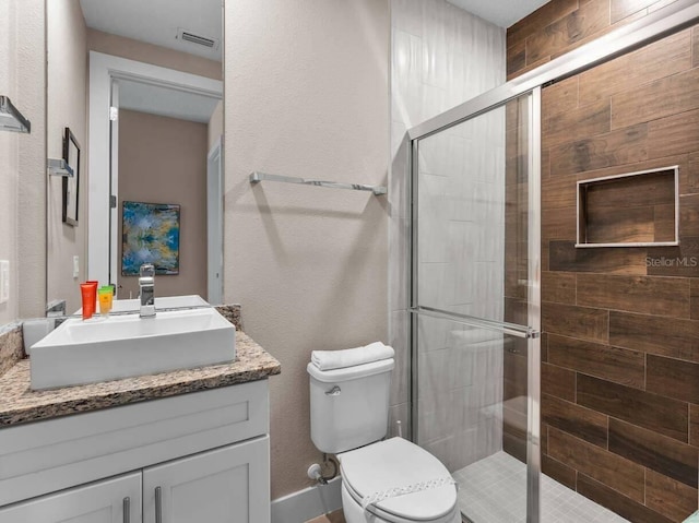 bathroom with vanity, a shower with door, and toilet