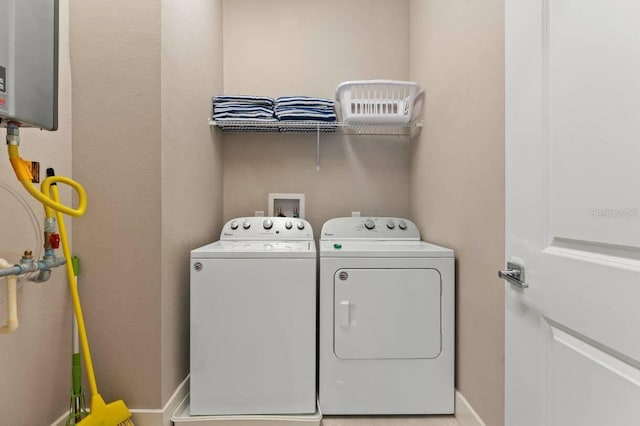 washroom with water heater and washing machine and dryer