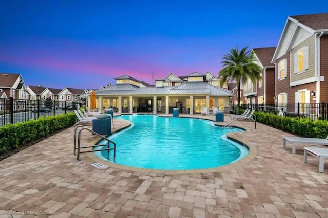 pool at dusk with a patio area