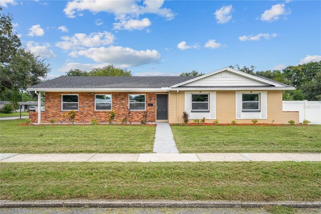 ranch-style home with brick siding, a front yard, fence, and a shingled roof