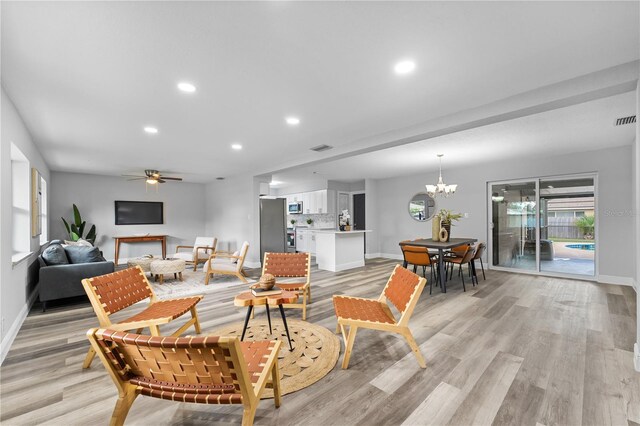 living room featuring light hardwood / wood-style floors and ceiling fan with notable chandelier