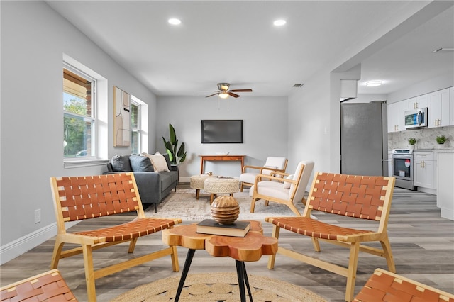 living room featuring visible vents, baseboards, ceiling fan, light wood-type flooring, and recessed lighting