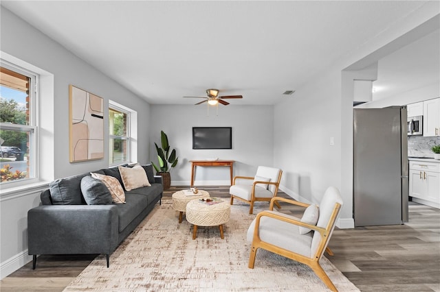 living room with wood finished floors, a ceiling fan, and baseboards