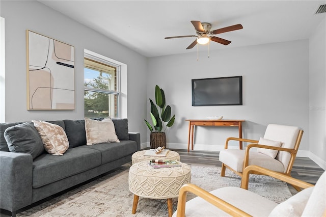 living area with a ceiling fan, visible vents, baseboards, and wood finished floors