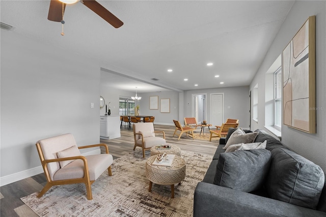 living area with recessed lighting, baseboards, visible vents, light wood-type flooring, and ceiling fan with notable chandelier