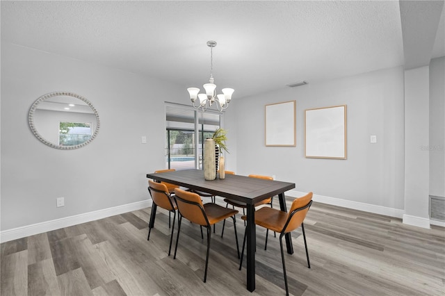 dining room with visible vents, a textured ceiling, baseboards, and wood finished floors