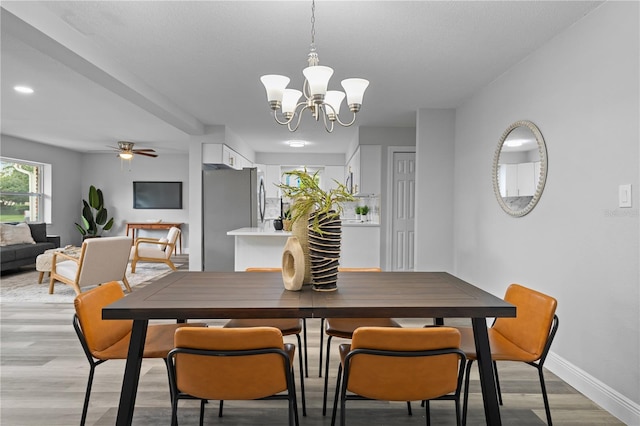 dining room featuring light wood finished floors, baseboards, and ceiling fan with notable chandelier