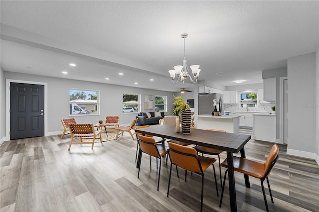 dining area featuring a wealth of natural light, an inviting chandelier, light wood-style flooring, and baseboards