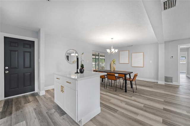 interior space featuring a chandelier, light wood finished floors, visible vents, and baseboards