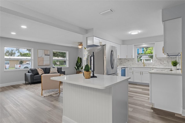 kitchen with light wood finished floors, visible vents, appliances with stainless steel finishes, open floor plan, and backsplash