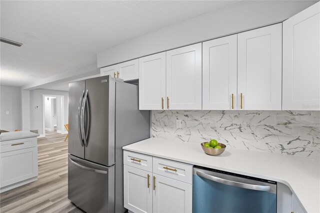 kitchen featuring appliances with stainless steel finishes, light countertops, white cabinets, and visible vents