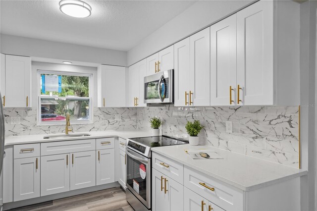 kitchen featuring stainless steel appliances, a sink, light countertops, and white cabinetry