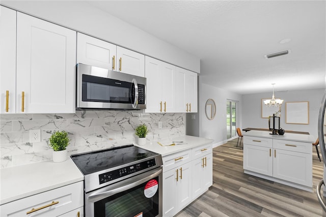 kitchen with visible vents, appliances with stainless steel finishes, wood finished floors, white cabinetry, and backsplash