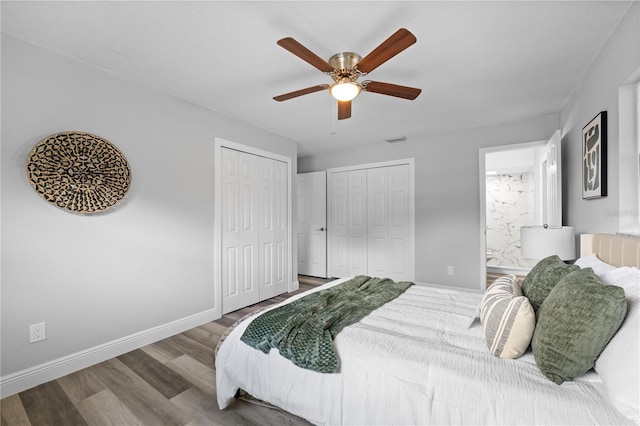 bedroom with multiple closets, baseboards, visible vents, and wood finished floors