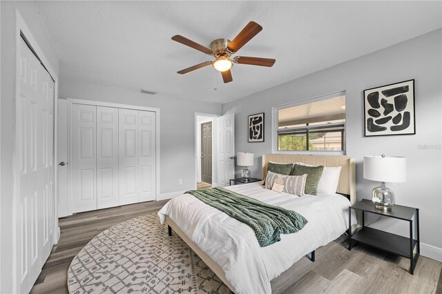 bedroom with baseboards, a closet, visible vents, and wood finished floors