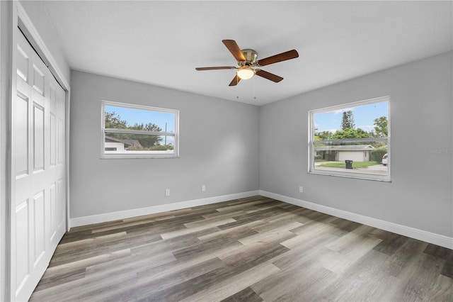 unfurnished bedroom featuring a closet, ceiling fan, baseboards, and wood finished floors