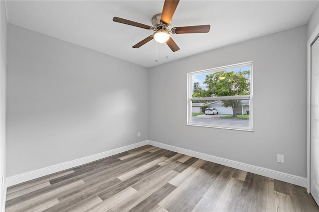 empty room featuring a ceiling fan, baseboards, and wood finished floors