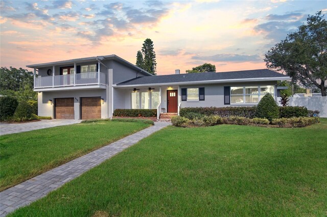 view of front of home featuring a balcony, a garage, and a yard