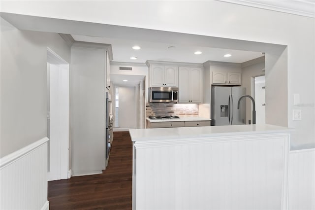 kitchen with ornamental molding, dark hardwood / wood-style floors, stainless steel appliances, and backsplash