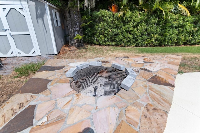 view of patio / terrace featuring a storage shed and an outdoor fire pit