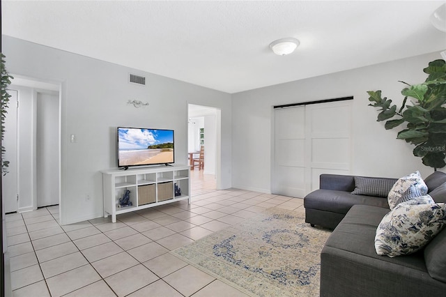 living room with light tile patterned floors, visible vents, and baseboards