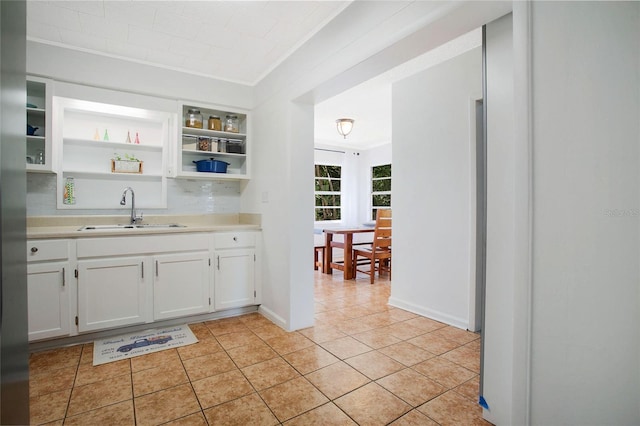 kitchen with light tile patterned flooring, crown molding, sink, and white cabinets